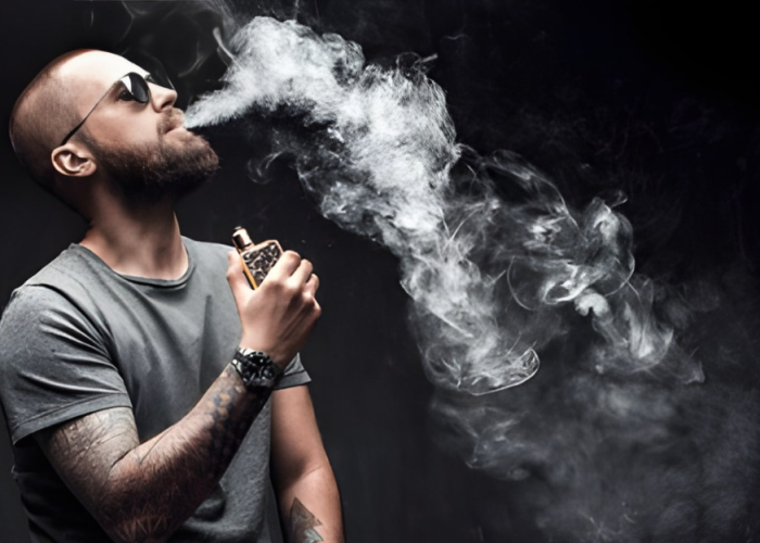 Man with a beard and sunglasses exhales a large cloud of vapor against a dark background, holding a vape device. The mood is relaxed and contemplative.